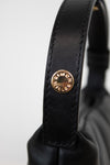 Close-up of a black leather strap with a gold logo on a white background