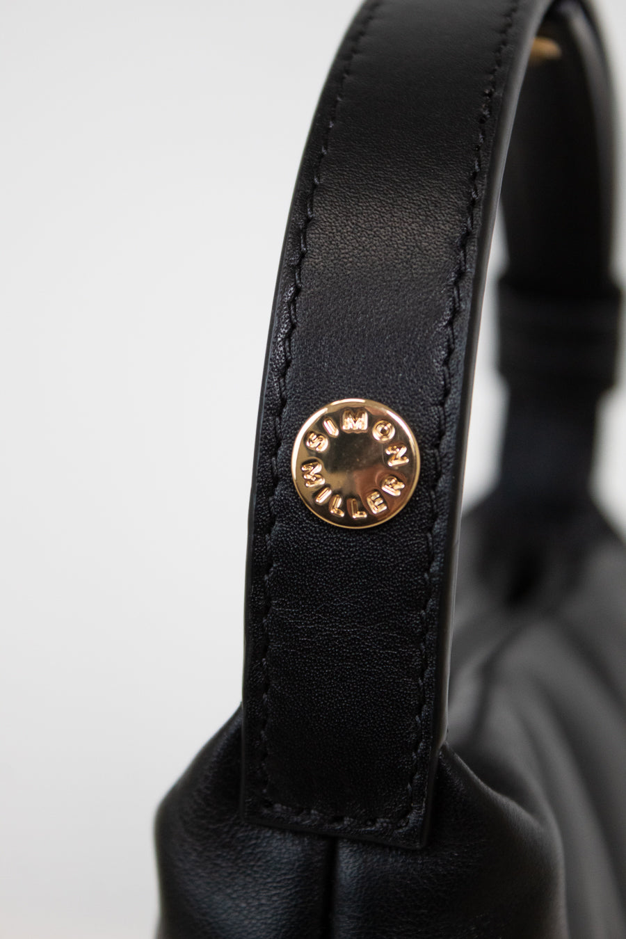 Close-up of a black leather strap with a gold logo on a white background