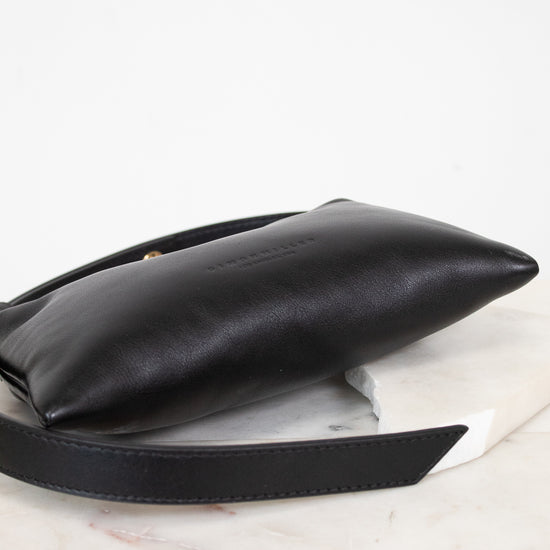 Black leather handbag on a light marble surface