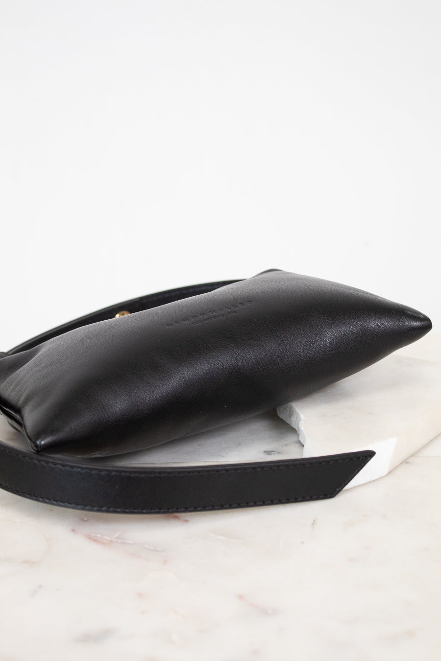 Black leather handbag on a light marble surface