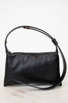 Black leather handbag with a strap on a light gray background