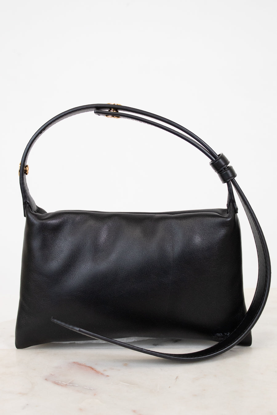 Black leather handbag with a strap on a light gray background
