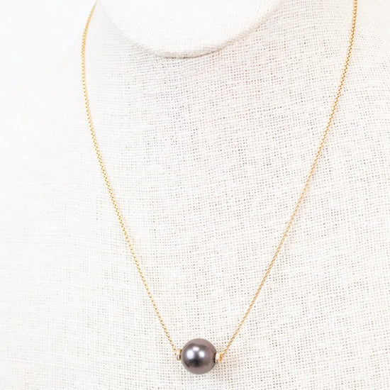Necklace with a single black pearl on a white background