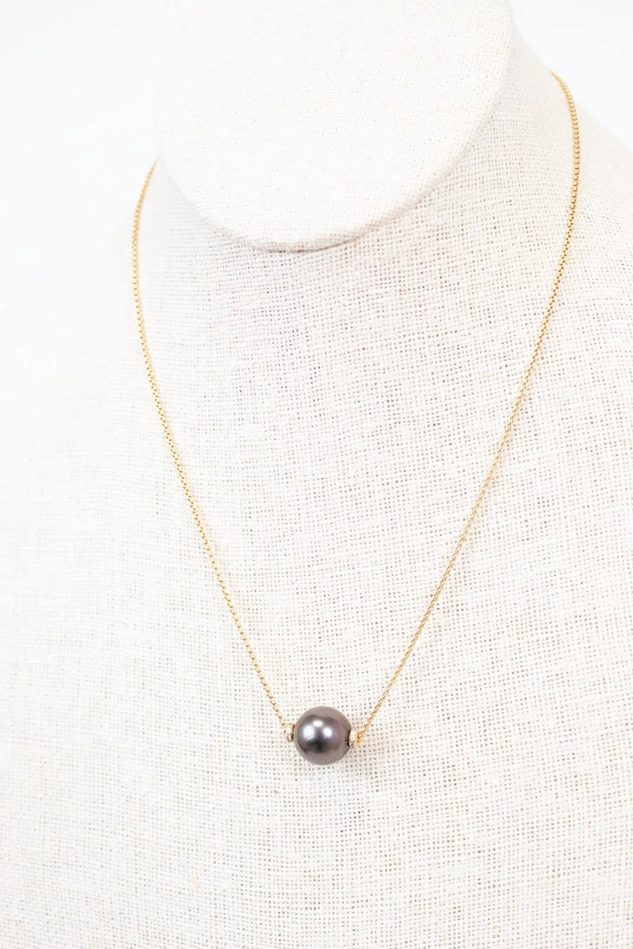 Necklace with a single black pearl on a white background
