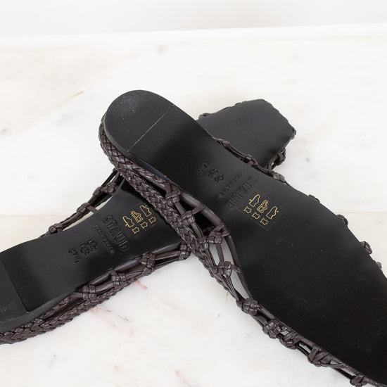 Dark brown sandal with woven detail on a light background