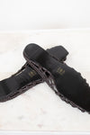 Dark brown sandal with woven detail on a light background