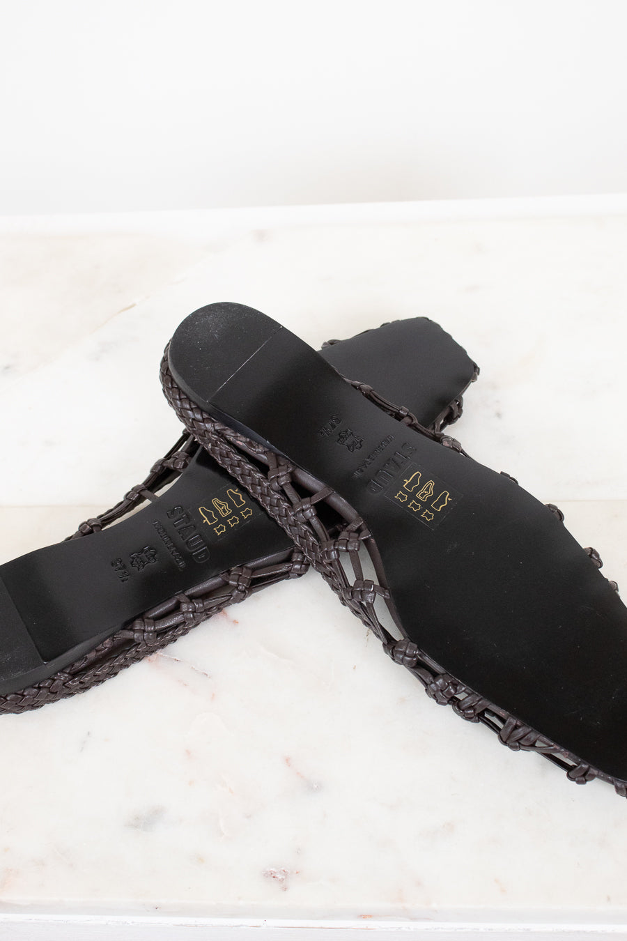 Dark brown sandal with woven detail on a light background