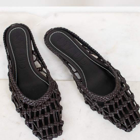 Dark brown woven sandals on a white marble surface