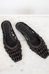 Dark brown woven sandals on a white marble surface