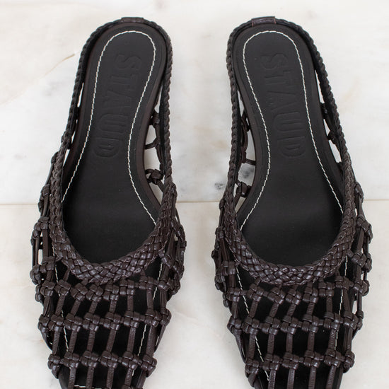 Pair of dark brown woven sandals on a light marble background