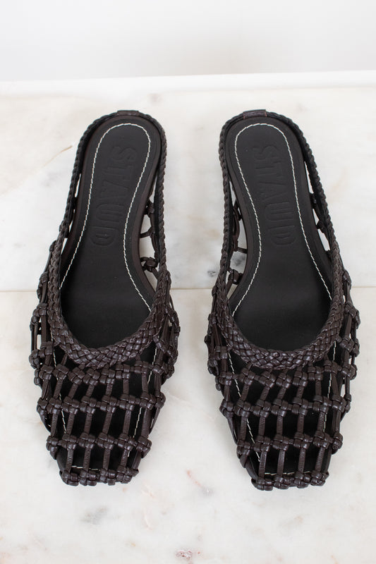 Pair of dark brown woven sandals on a light marble background