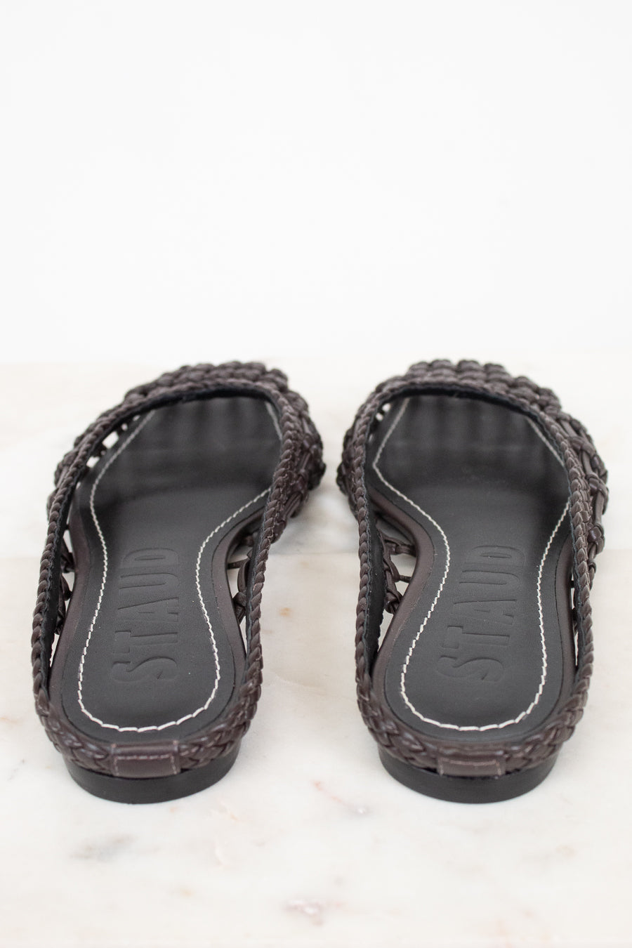 Pair of dark brown sandals with woven design on a white background