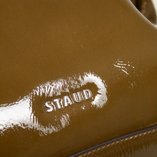 Close-up of an olive leather bag with 'Staud' logo branding.