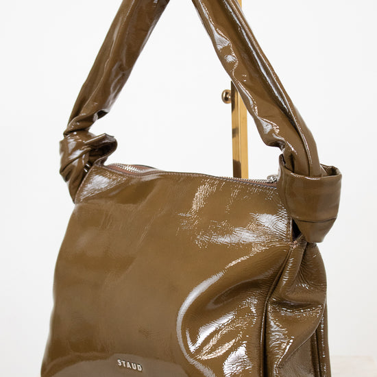 Olive patent leather handbag on a white background