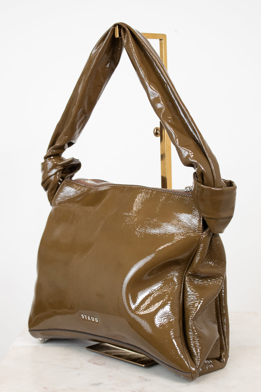 Olive patent leather handbag on a white background