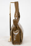 Olive patent leather handbag with a knotted handle detail on a white background
