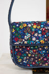Close-up of multicolored beaded handbag with floral patterns on a white background