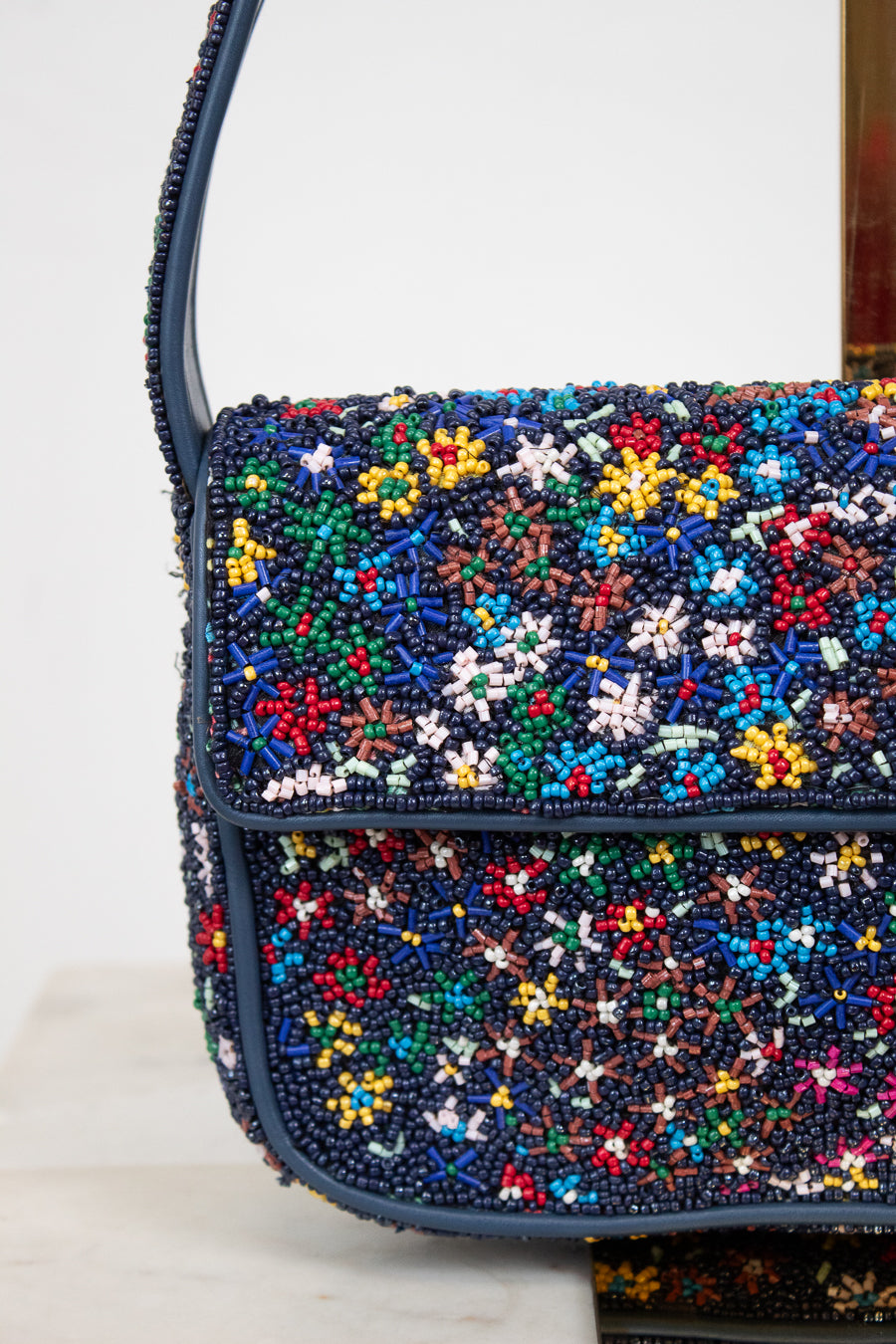 Close-up of multicolored beaded handbag with floral patterns on a white background