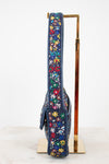 Side profile of handbag with colorful beaded floral pattern on a stand against a white background