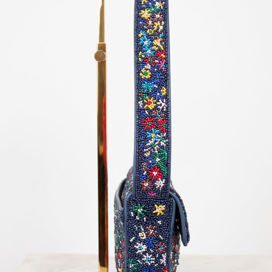 Floral-patterned side profile of beaded handbag strap on a stand against a white background