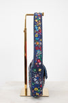 Floral-patterned side profile of beaded handbag strap on a stand against a white background