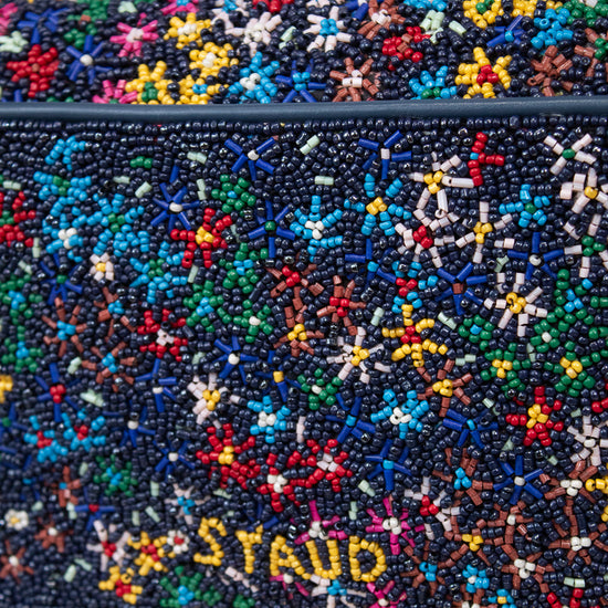 Multicolored beaded handbag with 'STAUD' branding on a light background