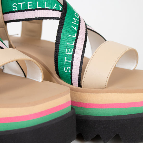 Beige sandals with colorful straps and 'Stella' branding on a light background