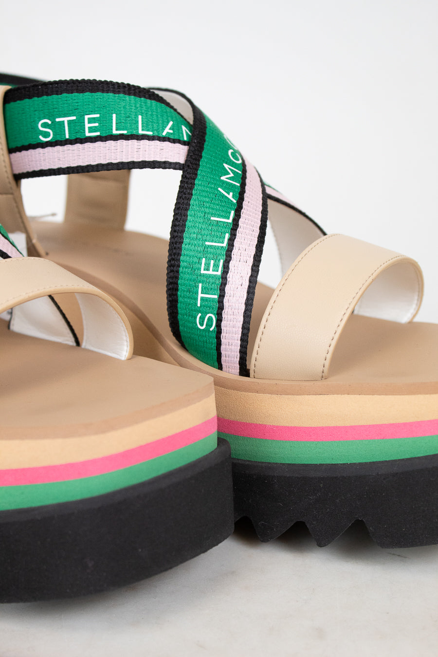 Beige sandals with colorful straps and 'Stella' branding on a light background