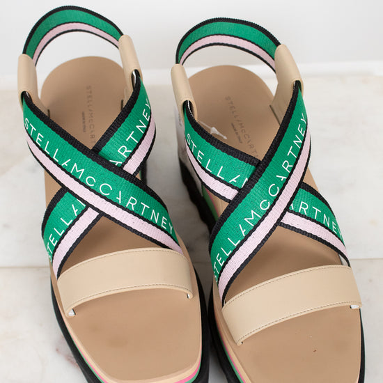 Beige sandals with green and pink straps on a white background