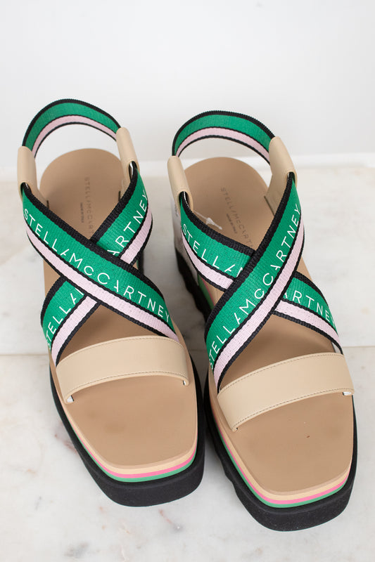 Beige sandals with green and pink straps on a white background