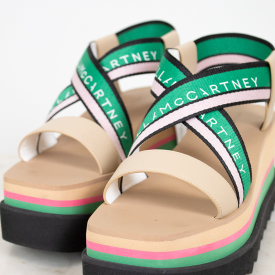 Pair of platform sandals with green and pink accents on a light background