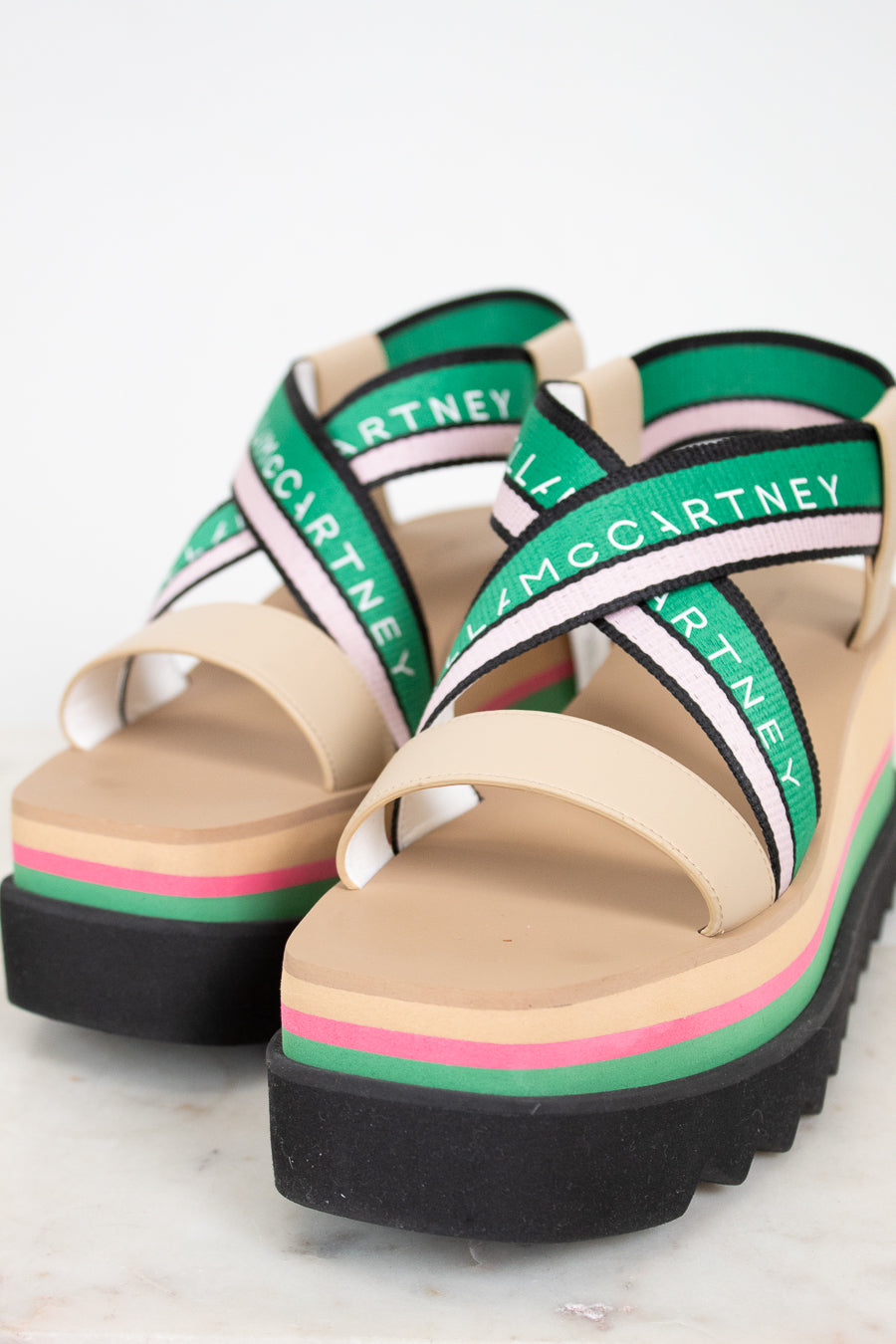 Pair of platform sandals with green and pink accents on a light background