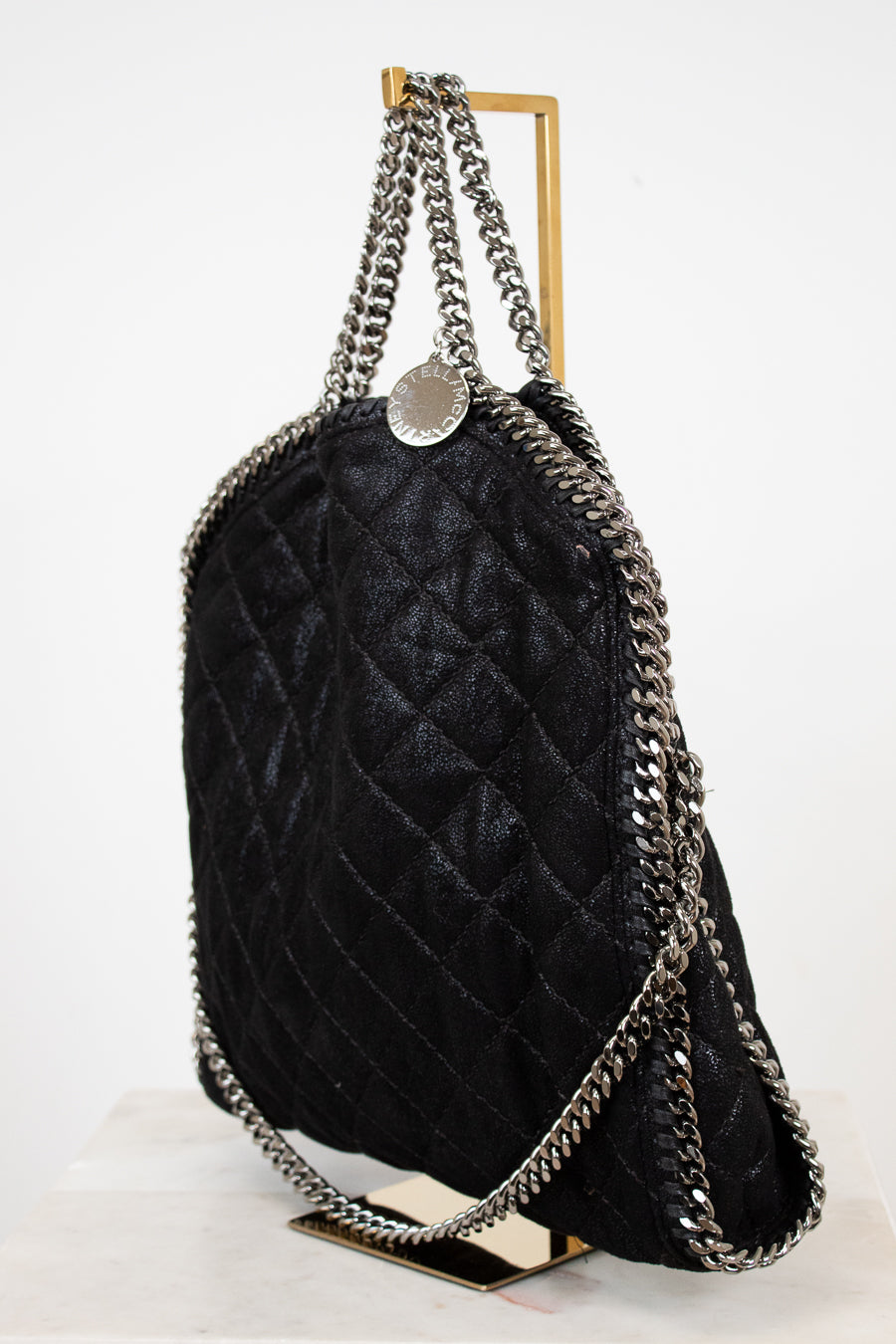 Black quilted handbag with silver chain straps on a white background