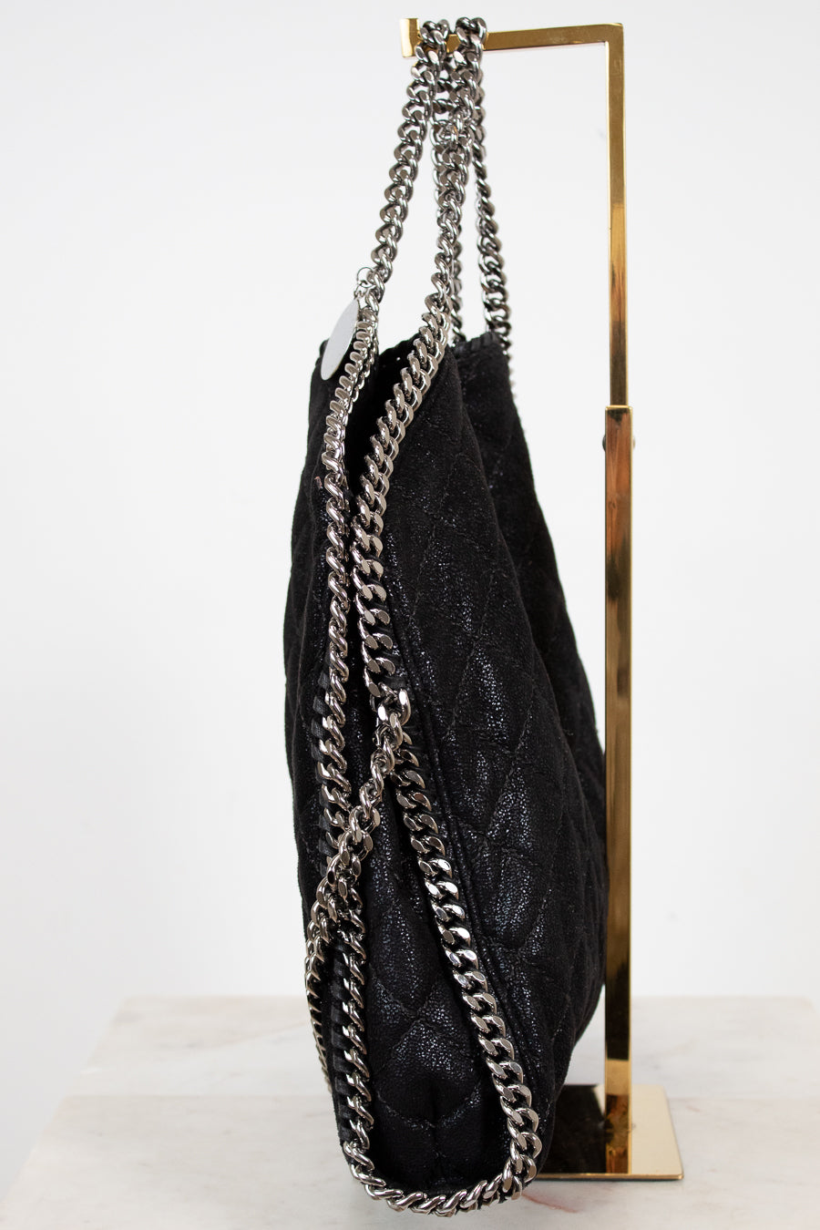 Black textured handbag with silver chain strap on a white background