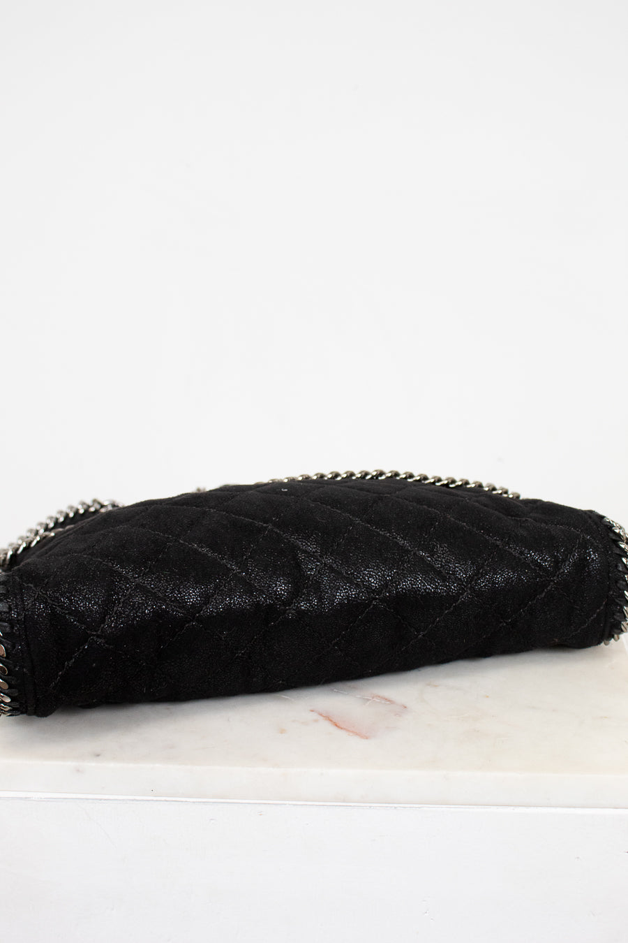 Black quilted bottom of bag on a white marble surface