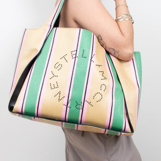 Person holding a striped tote bag with text on a plain background