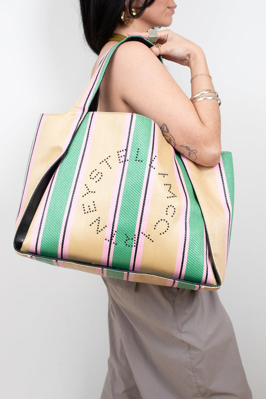 Person holding a striped tote bag with text on a plain background