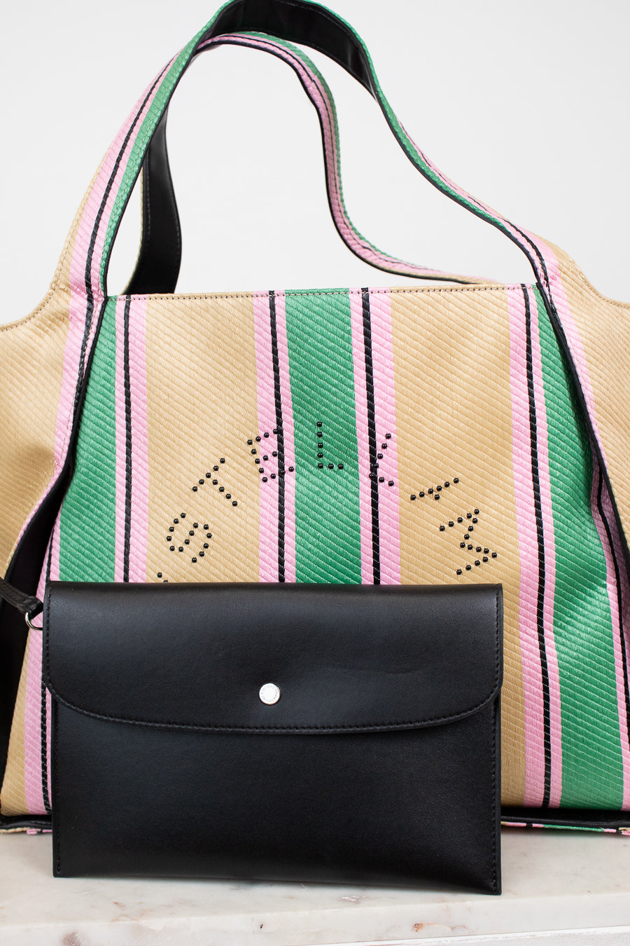 Handbag with colorful striped pattern and black flap on a white background