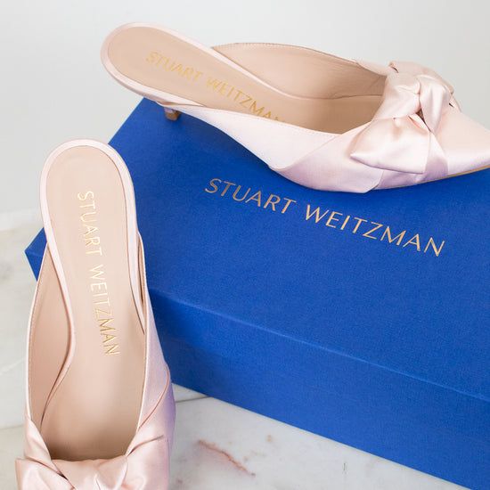 Pink satin shoes with bows on a Stuart Weitzman box
