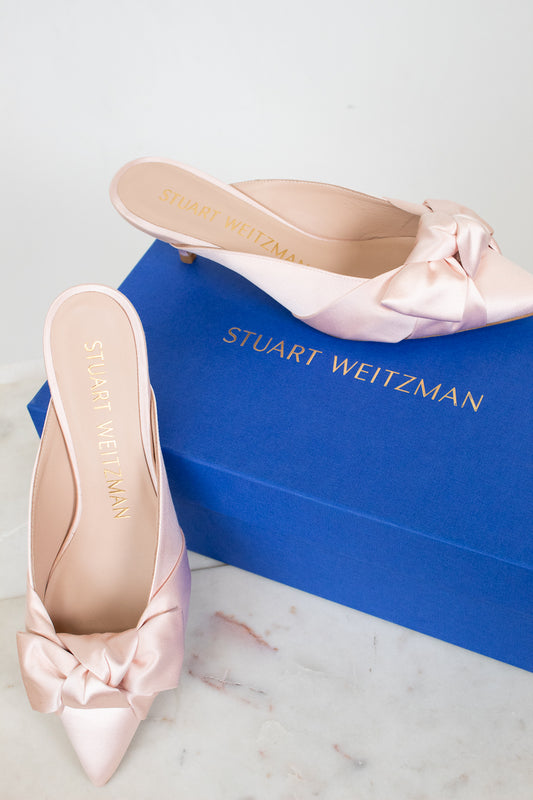 Pink satin shoes with bows on a Stuart Weitzman box