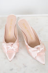 Pink kitten-heeled shoes with satin bows on a marble surface