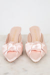 Pair of pink satin shoes with bows on a light background