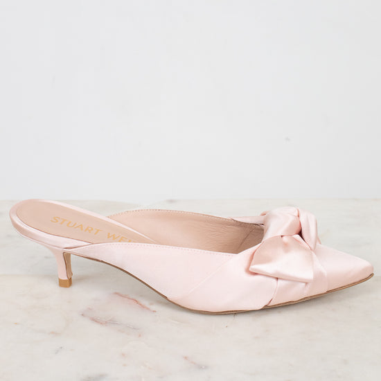 Pink kitten-heeled shoes with a bow on a marble surface