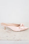 Pink kitten-heeled shoes with a bow on a marble surface