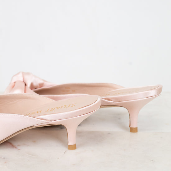 Pair of pink kitten-heeled shoes on a light marble surface