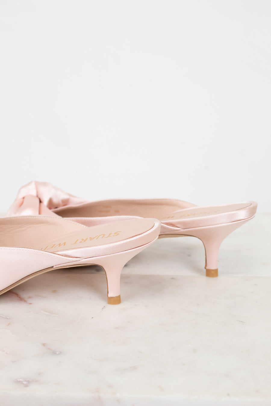 Pair of pink kitten-heeled shoes on a light marble surface