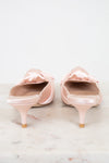 Pair of pink kitten-heeled shoes with bow details on a light background