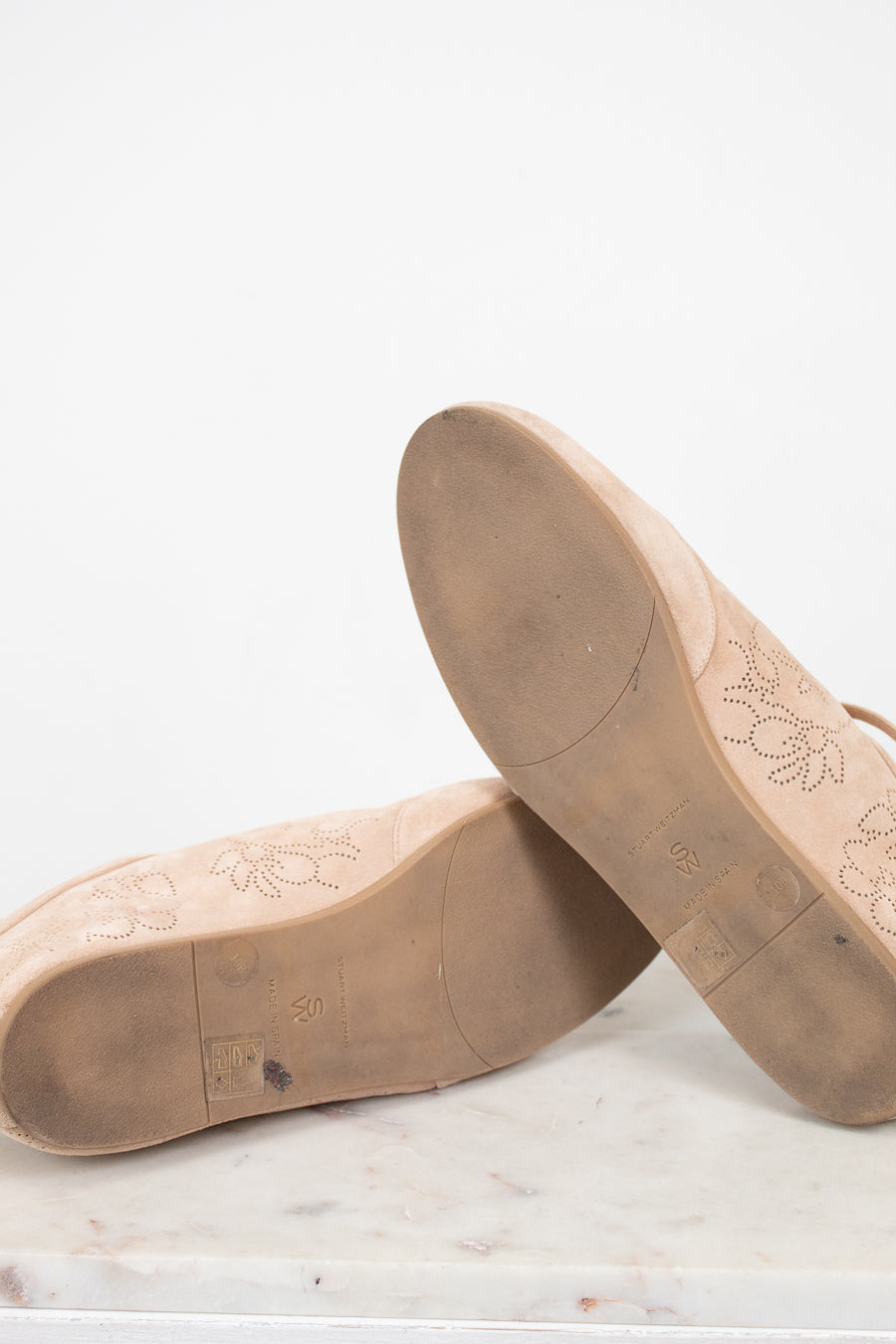 Brown leather shoe soles on a marble surface with a white background