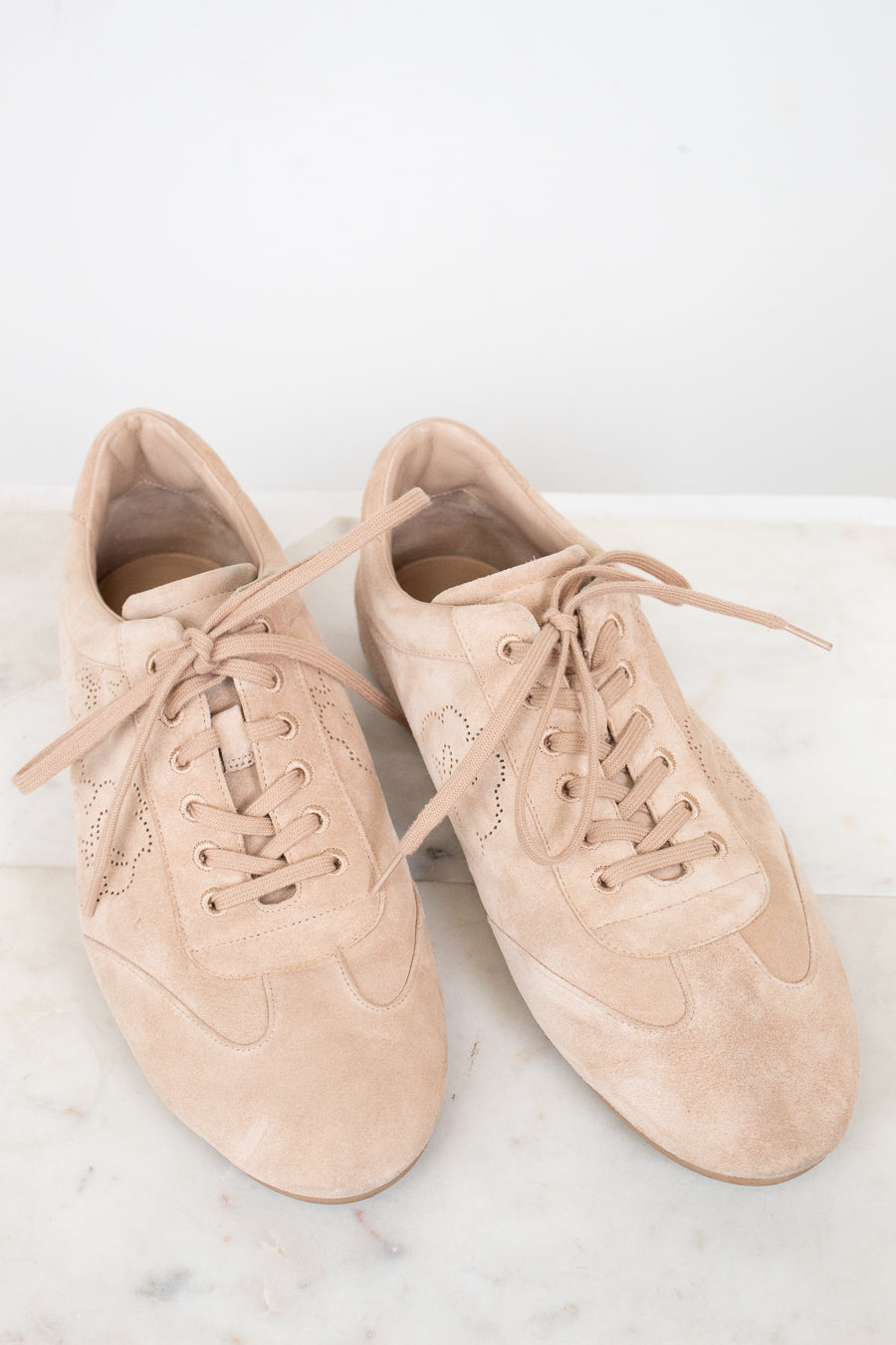 Pair of beige sneakers on a light marble surface