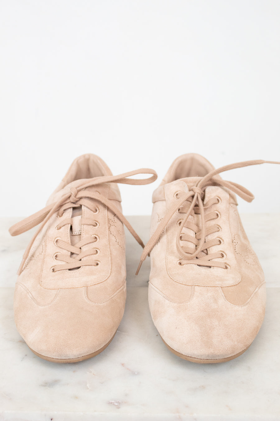 Pair of beige sneakers on a light marble surface